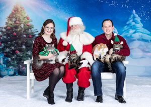Family with four cats sitting for posed christmas picture with santa